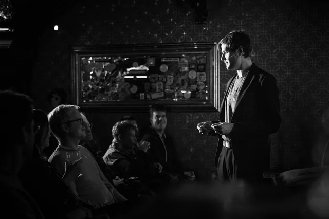 Black and white photo of Neven performing for a seated audience